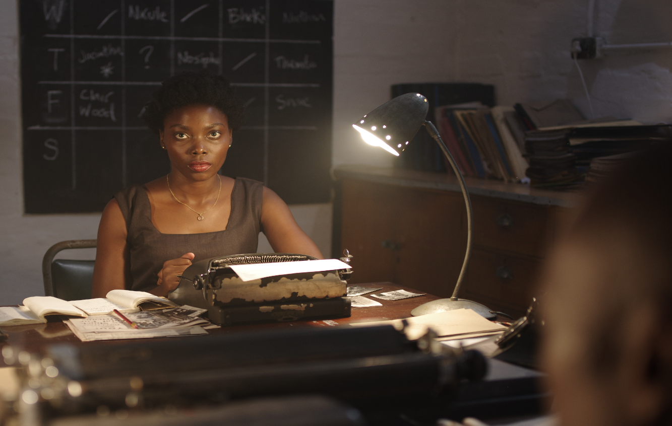 A person sitting at a desk with a typewriter

Description automatically generated